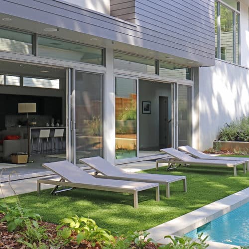 Compact backyard with pool and lounge area with artificial turf
