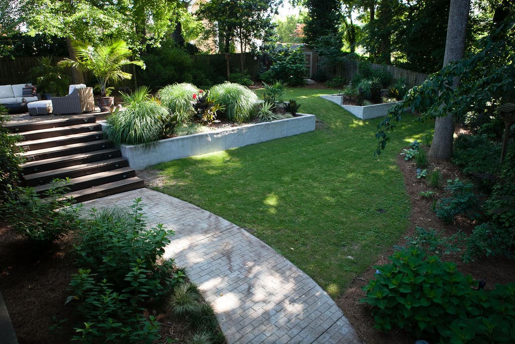 Sloped shady backyard with raised beds as retention