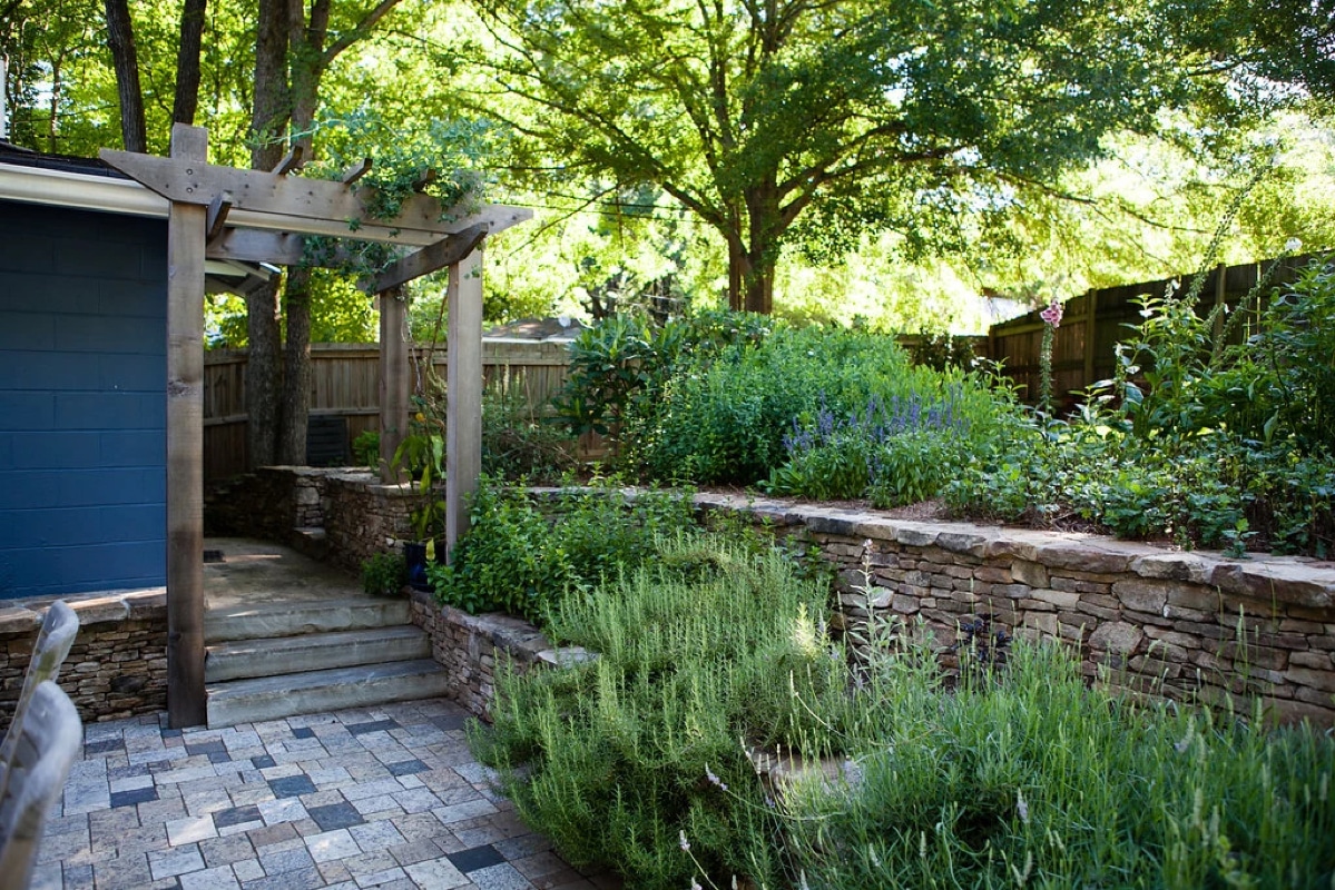 Wooden arbor and natural stone terraced walls for herb garden