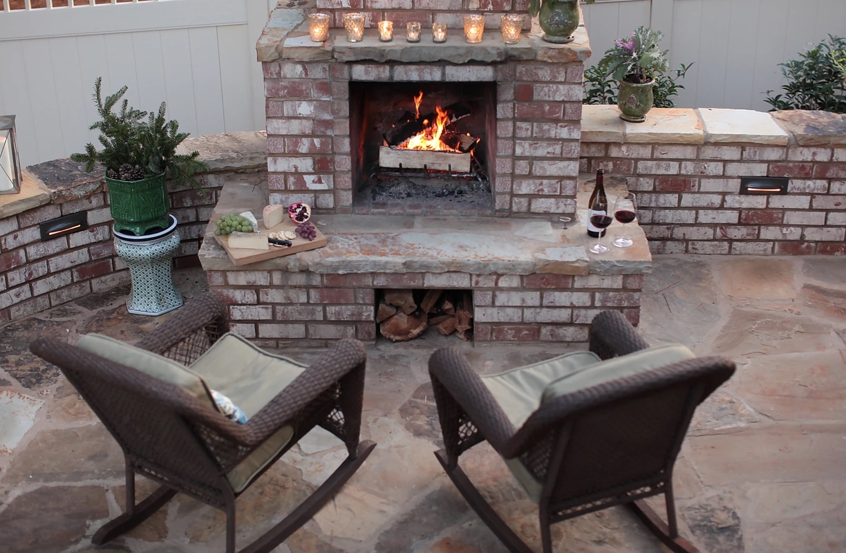 Brick and stone backyard patio with fireplace and seat wall