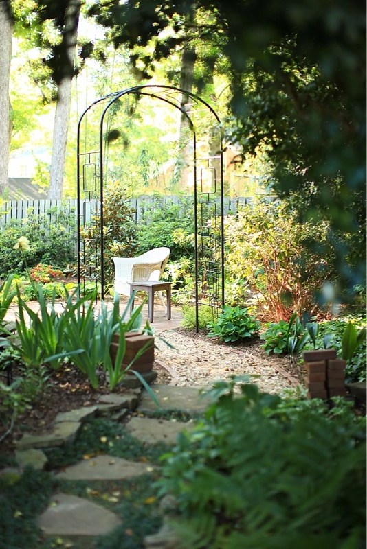 Quiet backyard space with stepping stones and metal arbor