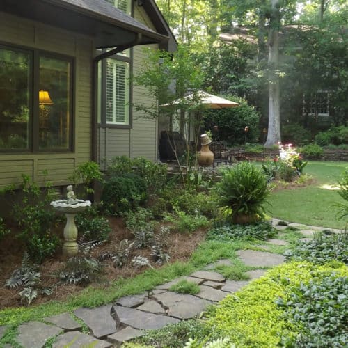 City backyard with natural stone pathway, shade plants and lawn area