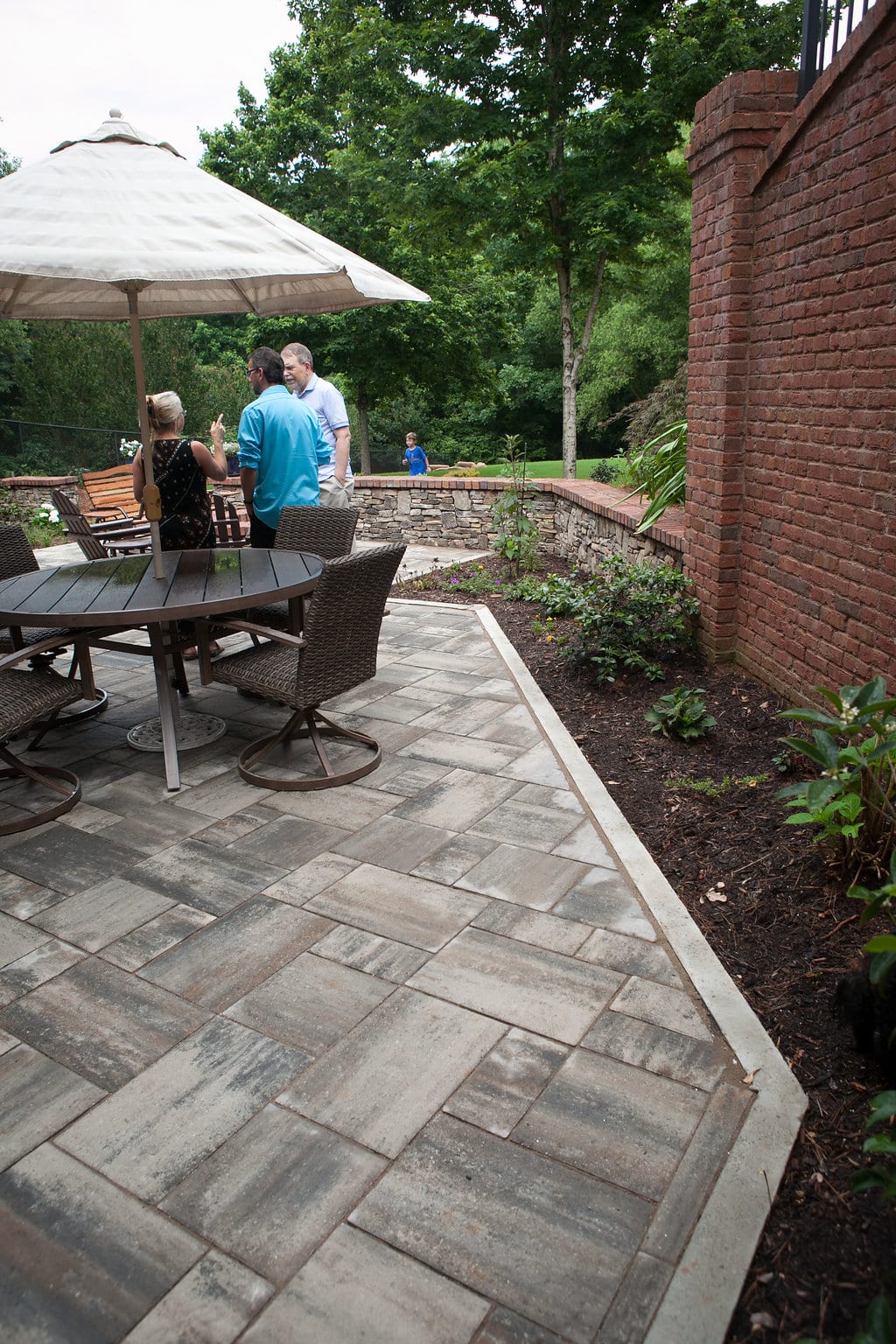 Contemporary backyard patio space with Belgard concrete pavers and poured concrete edge