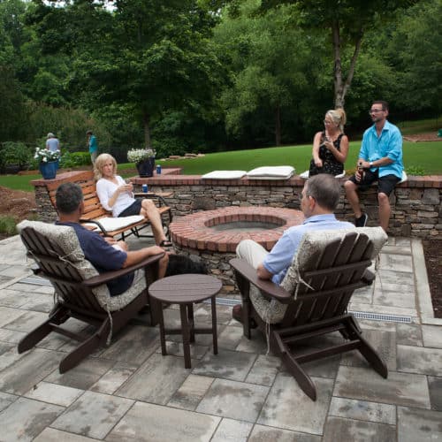Concrete paver backyard patio, stone clad seat wall and fire pit with brick cap