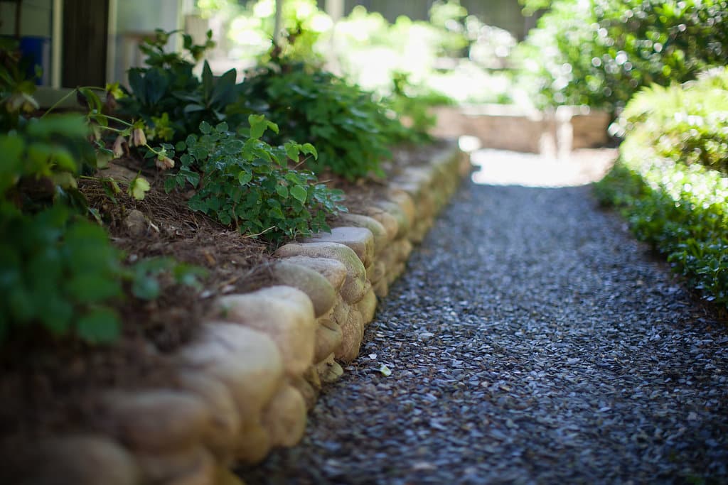 Crushed slate path with river rock raised bed